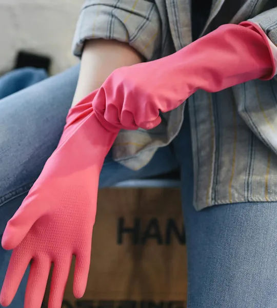 Frau zieht Gummihandschuhe an